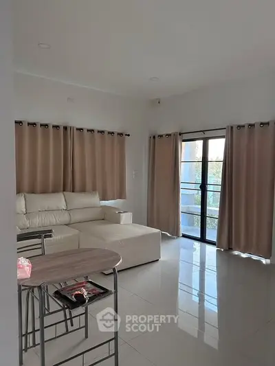 Modern living room with sleek white furniture and large windows for natural light.