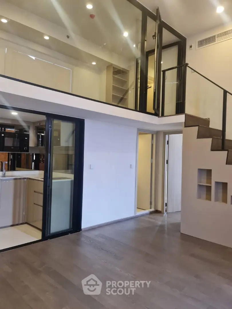 Modern duplex apartment with high ceilings, sleek kitchen, and elegant staircase leading to an upper level, perfect for urban living.