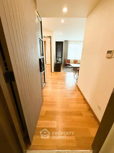 Modern apartment entrance with wooden flooring and stylish living room view.