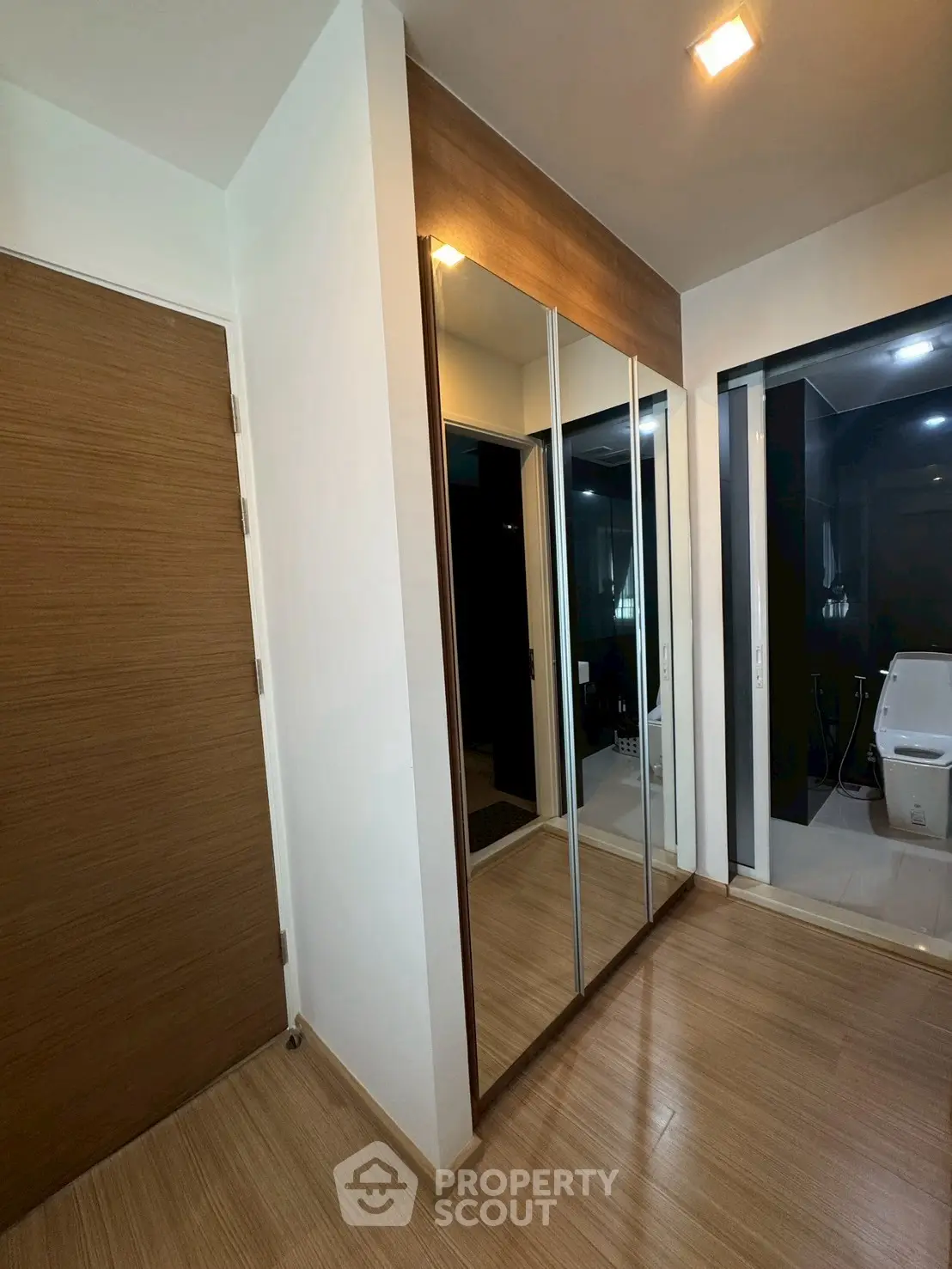 Modern bathroom with sleek wooden flooring and mirrored closet doors