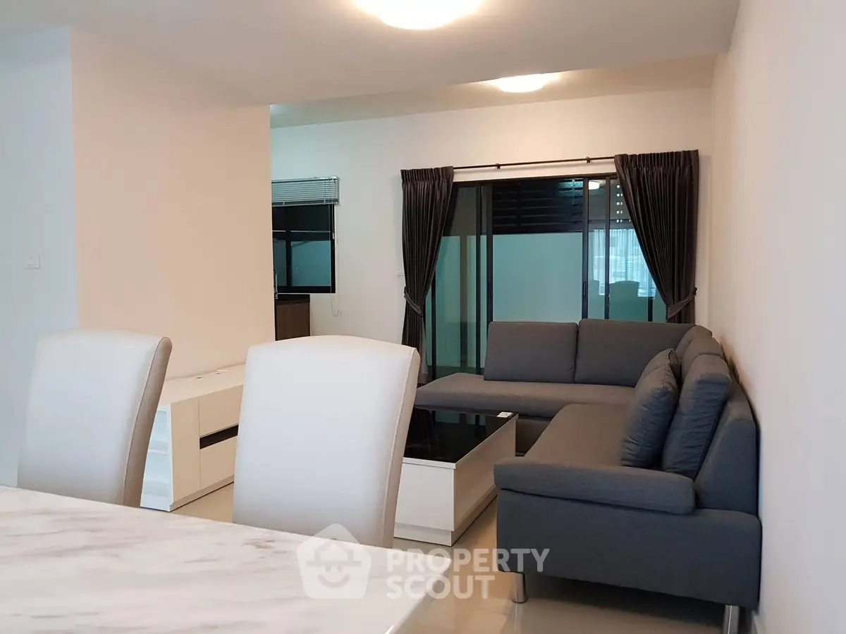 Spacious modern living room with elegant gray sectional sofa and sleek white furniture.