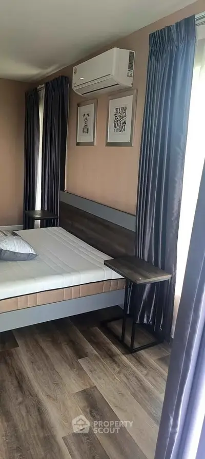 Modern bedroom with stylish decor and air conditioning, featuring elegant curtains and wood flooring.