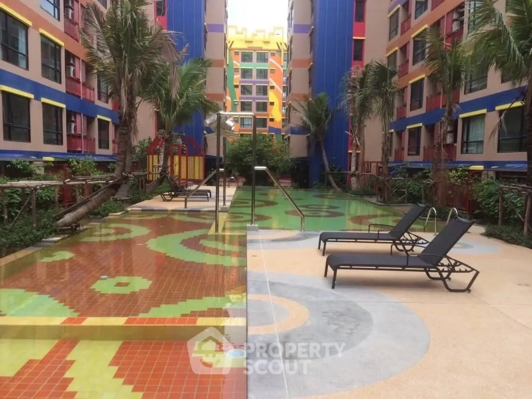 Vibrant apartment complex with colorful pool area and lounge chairs, perfect for relaxation.