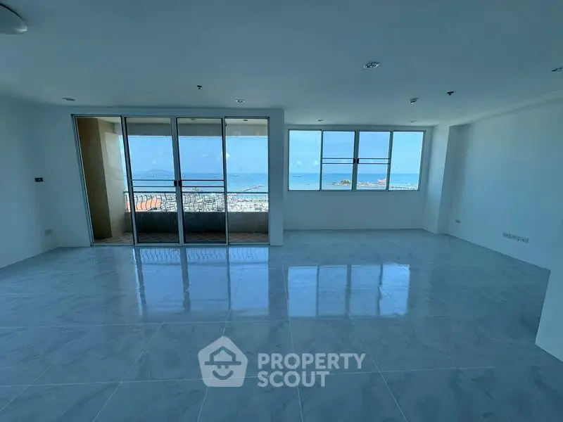 Spacious living room with stunning ocean view and large windows in modern apartment.