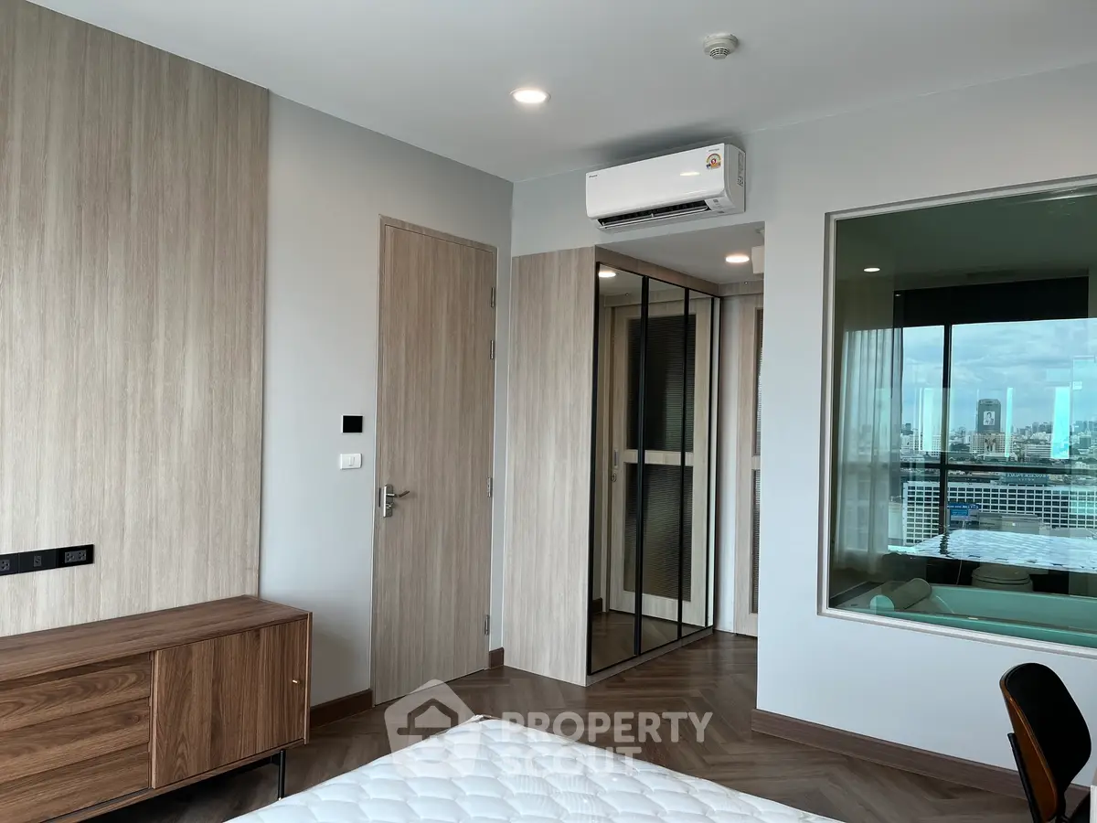 Modern bedroom with city view, featuring sleek wood finishes and air conditioning.