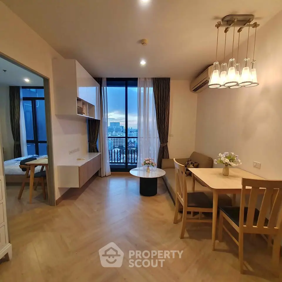 Modern living room with dining area and city view, featuring elegant lighting and cozy furnishings.