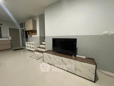 Modern living room with sleek TV stand and staircase, perfect for contemporary homebuyers.