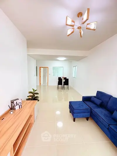 Spacious modern living room with blue sofa and elegant lighting, perfect for relaxation and entertainment.
