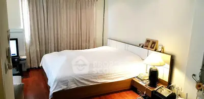 Cozy bedroom with wooden flooring and elegant decor, featuring a large bed and soft lighting.