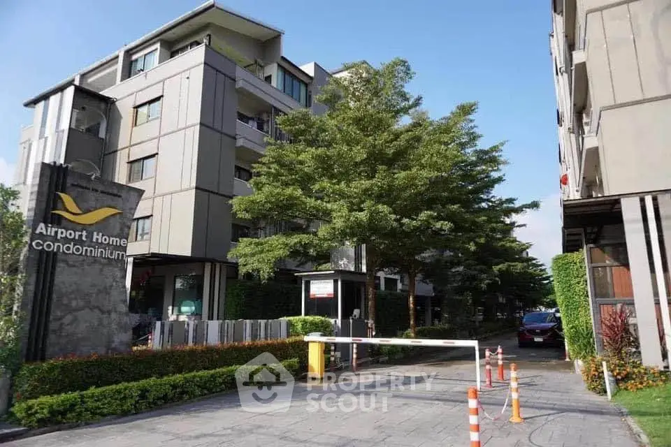 Modern condominium exterior with lush greenery and secure entrance near airport.
