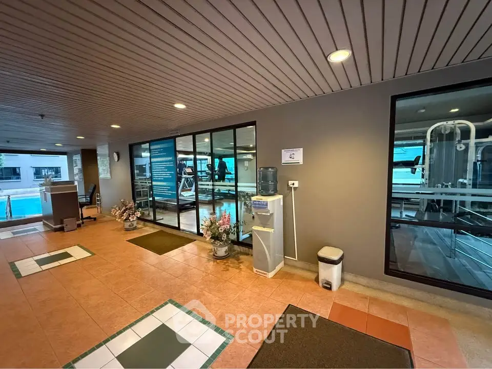 Modern gym entrance with glass walls and water cooler, inviting fitness enthusiasts.