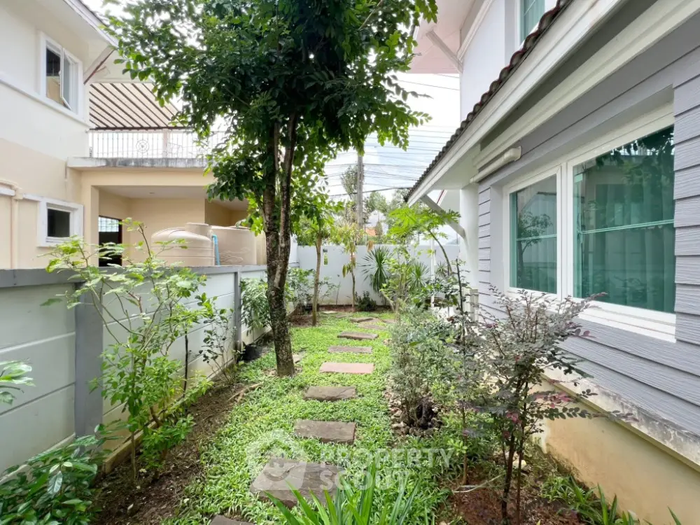 Charming garden pathway in residential property with lush greenery and modern exterior design.