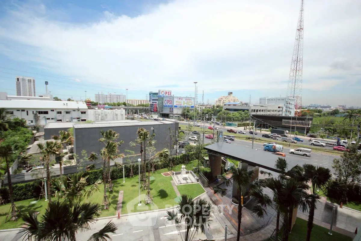 Stunning cityscape view from a high-rise building with lush greenery and urban skyline.