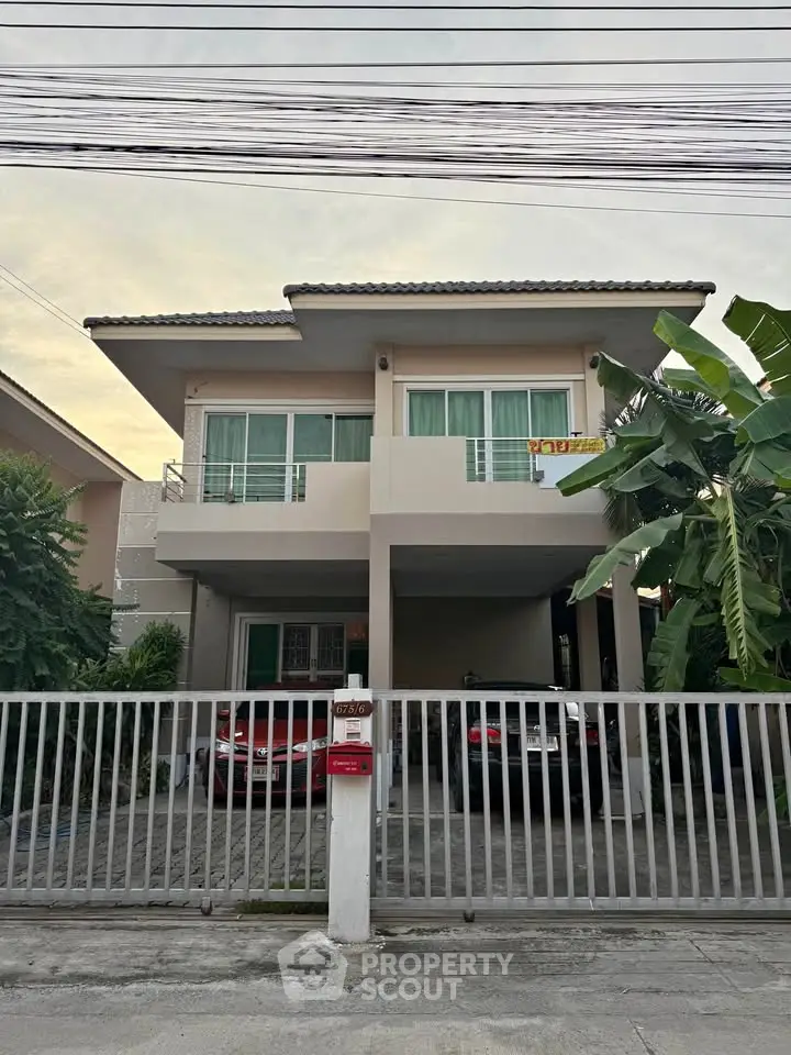 Modern two-story house with gated parking and lush greenery