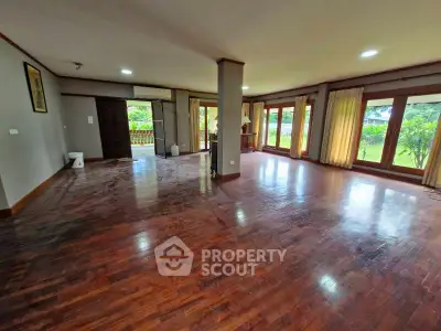 Spacious living room with hardwood floors and large windows offering garden views.
