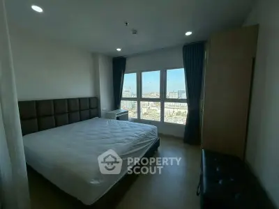 Spacious bedroom with large window offering stunning city views, modern furnishings, and ample natural light.
