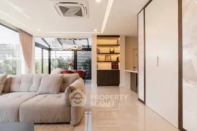 Luxurious living room with plush sofa and modern decor, featuring large windows and elegant lighting.