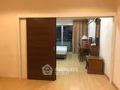 Spacious studio apartment with wooden sliding door and city view.