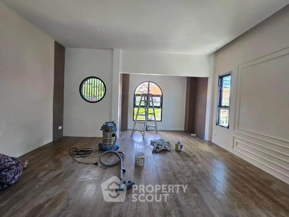 Spacious room under renovation with modern flooring and unique window design