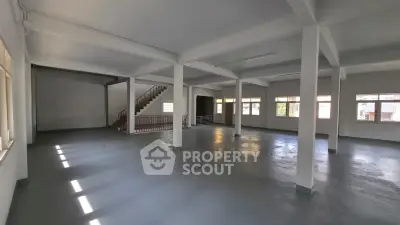 Spacious open-plan interior with large windows and staircase, ideal for versatile use.
