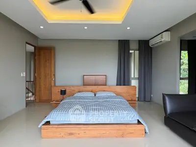 Spacious modern bedroom with wooden bed frame and large windows offering natural light.