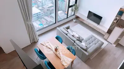 Modern living room with large windows and stylish furniture offering city views.
