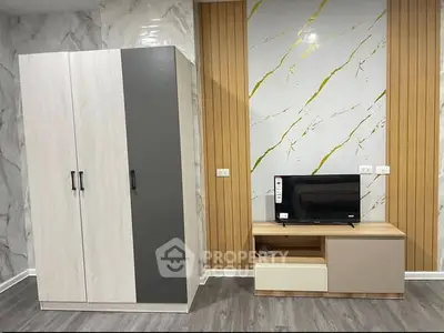Modern living room with stylish wardrobe and TV unit, featuring elegant wall design and sleek flooring.