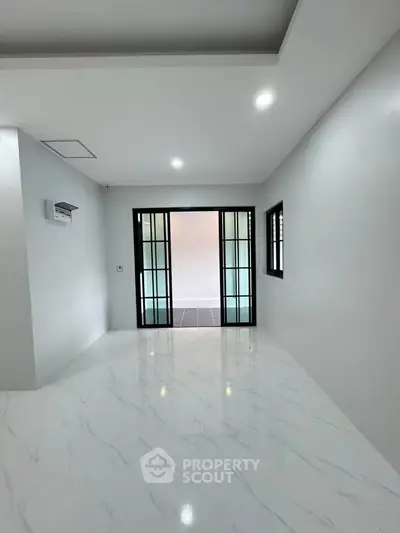 Spacious modern interior with sleek white flooring and sliding glass doors, perfect for contemporary living.