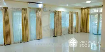 Spacious and well-lit living room with gleaming white tiles and elegant golden drapes, perfect for luxurious living.