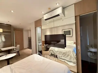 Modern studio apartment with mirrored walls and sleek furnishings, featuring a cozy bed and dining area.