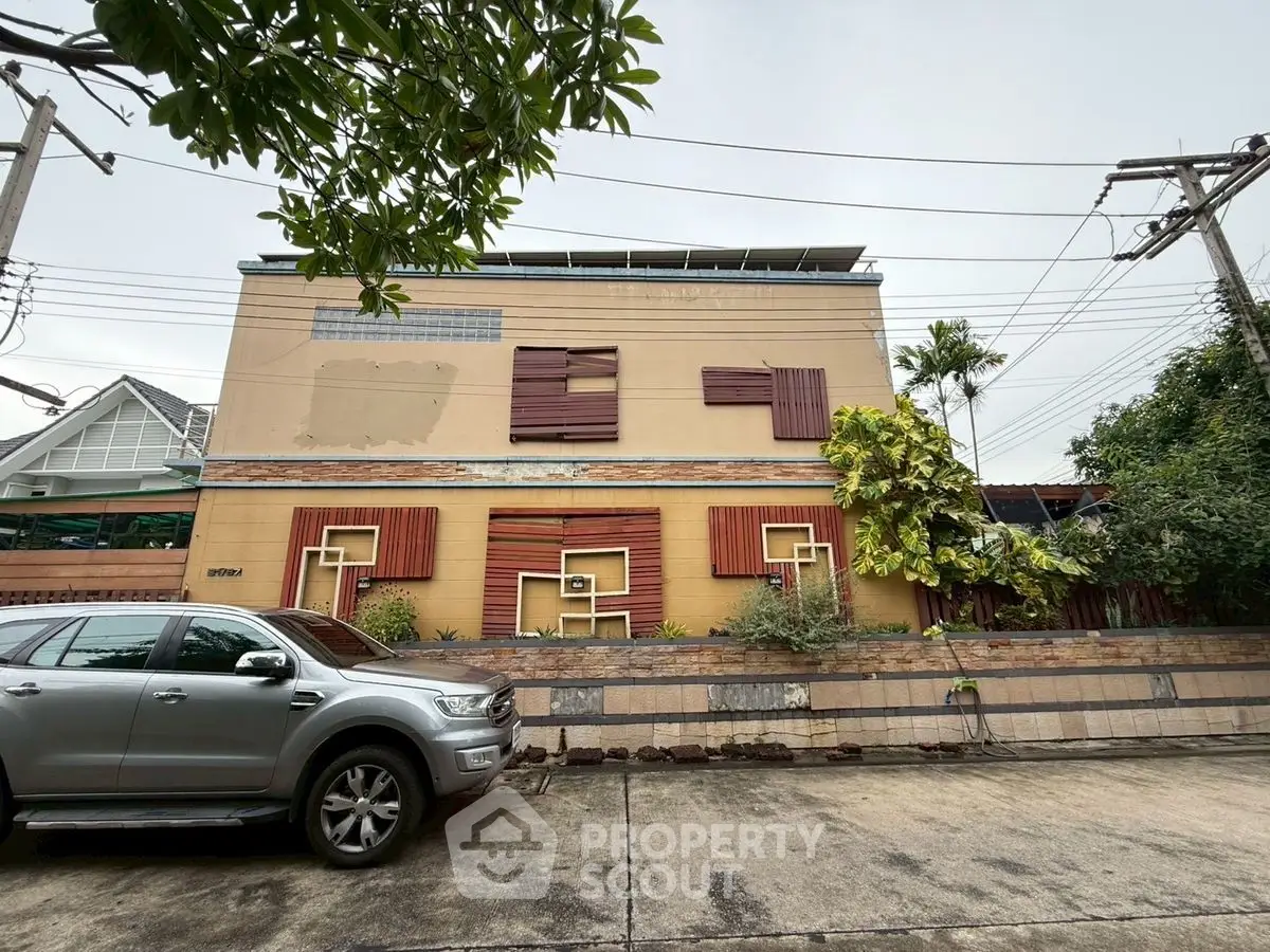 Unique modern house exterior with creative wooden accents and lush greenery on a quiet street.