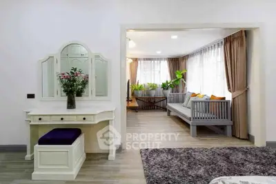 Spacious living room with elegant decor and natural light, featuring a cozy seating area and stylish vanity.