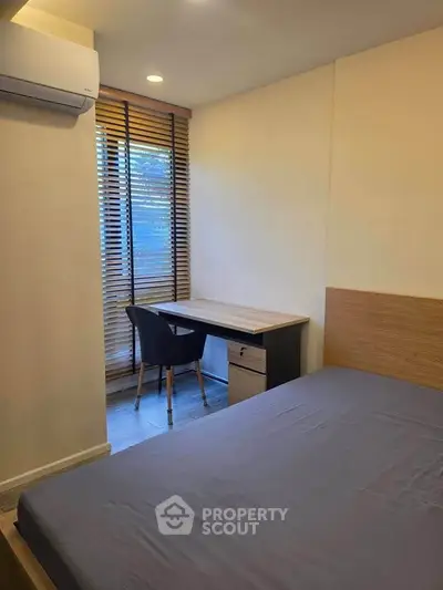 Cozy bedroom with study area and natural light, perfect for modern living.