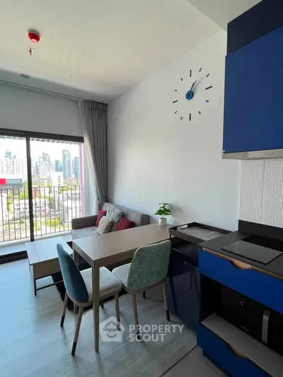 Modern living room with city view, stylish furniture, and open kitchen layout.