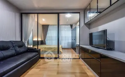 Modern apartment with sleek living room and cozy bedroom separated by glass partition.