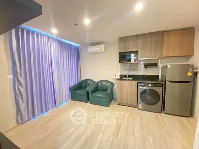 Modern studio apartment with kitchenette, washing machine, and cozy seating area.
