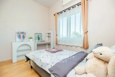 Cozy bedroom with plush decor and natural light, perfect for relaxation.