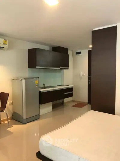 Modern studio apartment with compact kitchen and sleek cabinetry, ideal for urban living.