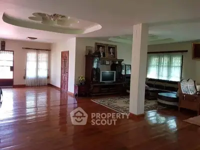 Spacious living room with polished wooden floors and elegant furniture, perfect for family gatherings.