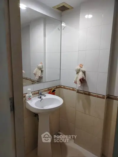 Compact bathroom with pedestal sink and wall mirror, ideal for small spaces.