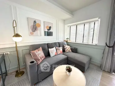 Chic living room with modern decor, cozy gray sofa, stylish artwork, and natural light from large window.