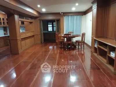 Spacious wooden-floored living area with dining set and built-in cabinets