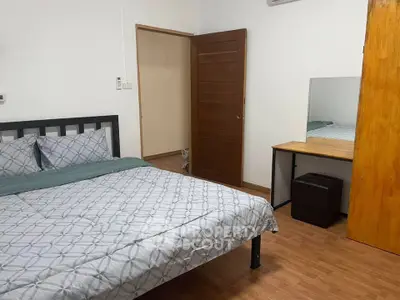 Cozy bedroom with modern decor and wooden flooring, featuring a comfortable bed and a stylish desk area.