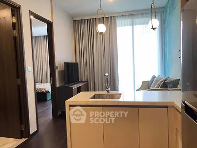 Modern open-layout kitchen with island and cozy living area in stylish apartment.