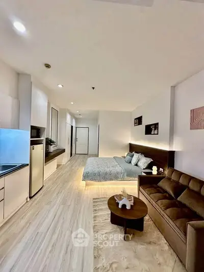 Modern studio apartment with sleek design, featuring a cozy bed, stylish sofa, and compact kitchen area.