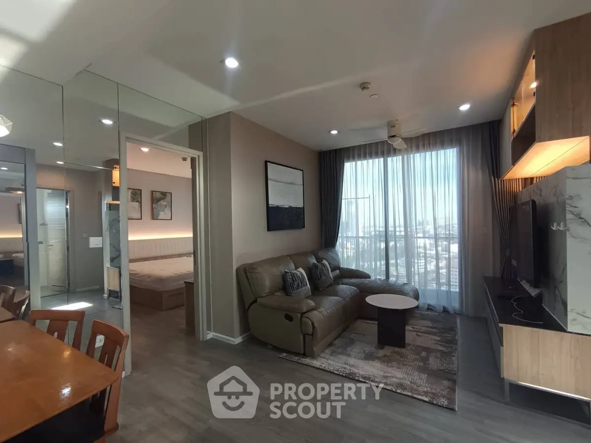 Modern living room with cozy sofa, stylish decor, and large window offering city views in a contemporary apartment.
