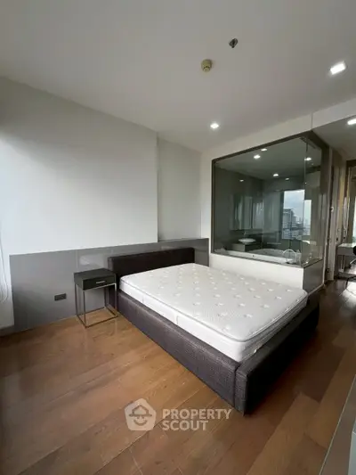 Modern bedroom with hardwood floors and large window offering city views