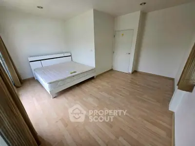 Spacious bedroom with wooden flooring and natural light, perfect for relaxation.
