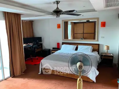 Spacious bedroom with modern decor and work desk, featuring a ceiling fan and large mirror.