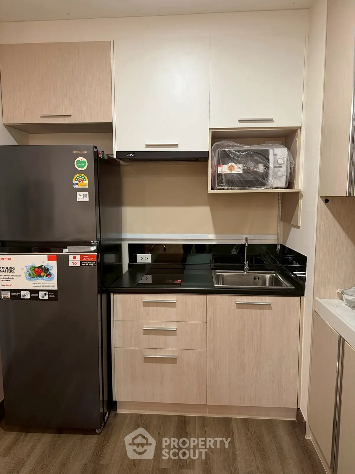Modern kitchen with sleek cabinetry, black countertop, and stainless steel appliances in a stylish apartment.